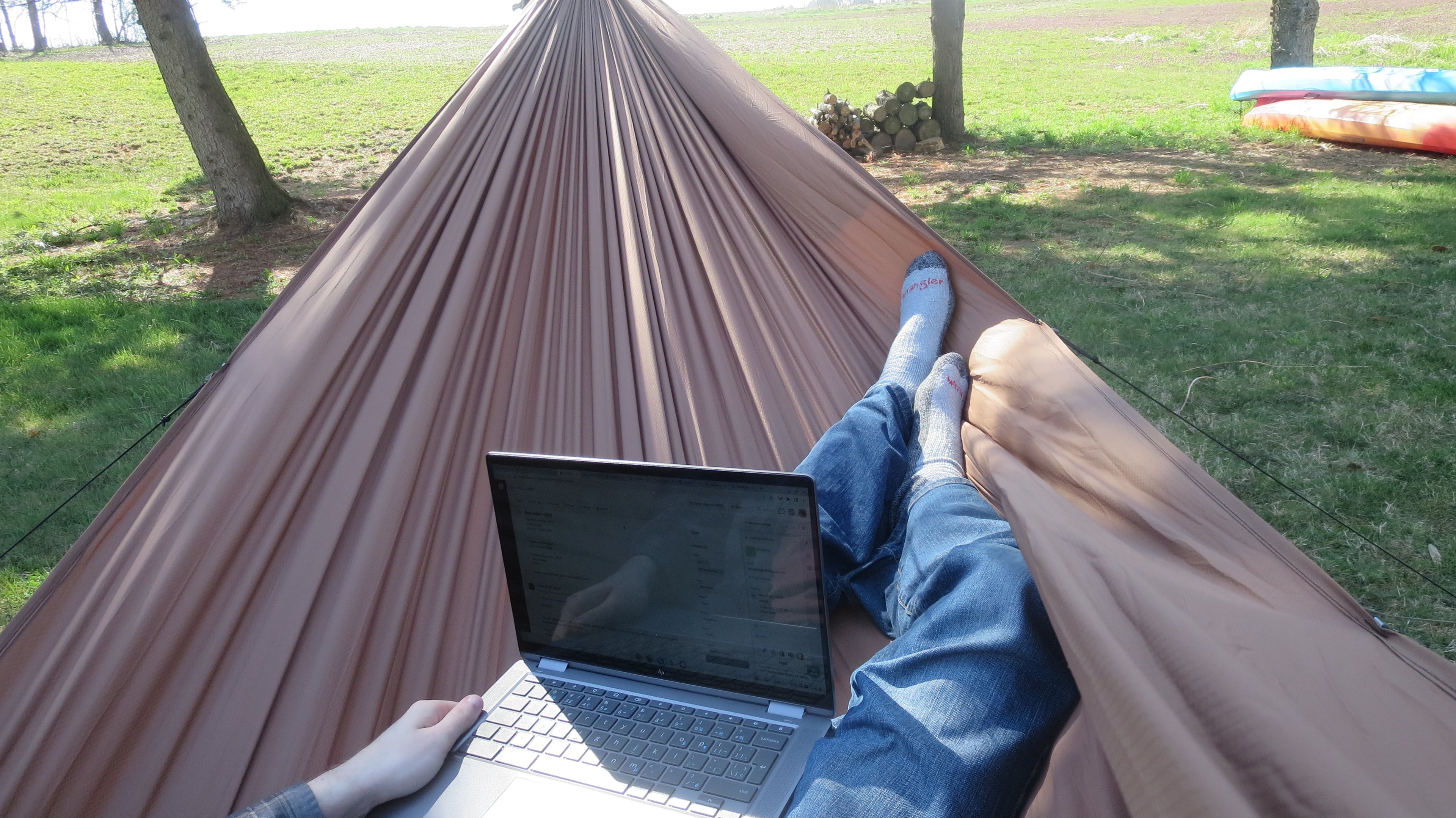 Working on a computer while laying in a coyote brown freebird - netless camping hammock or backpacking hammock