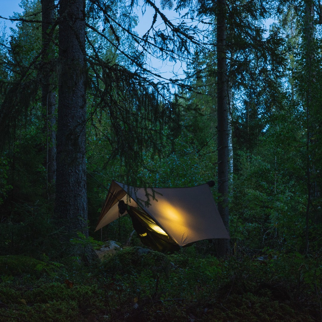 ultralight camping hammock at night with a glowing light from the tarp and underquilt custom made dream hammock with bugnet or mosquito net